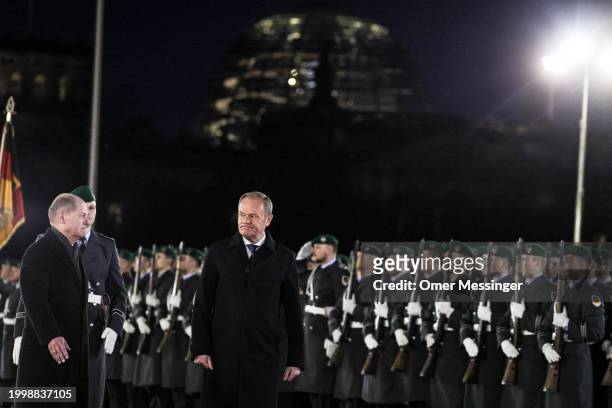 German Chancellor Olaf Scholz and Polish Prime Minister Donald Tusk review a guard of honor upon Tusk's arrival for talks at the Chancellery on...