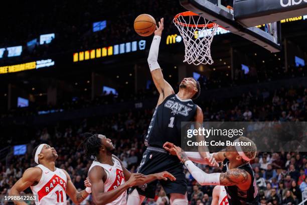 Victor Wembanyama of the San Antonio Spurs grabs a rebound from Bruce Brown and Immanuel Quickley of the Toronto Raptors in the second half of their...