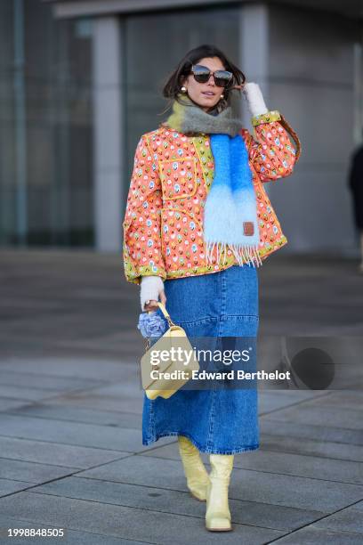 Guest wears sunglasses, a khaki / gray / blue wool fringed scarf, an orange floral print padded jacket with yellow lines, a pastel pale Vuitton bag,...