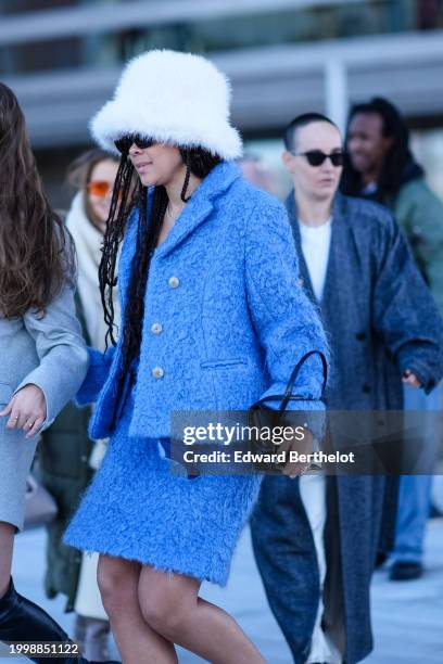 Guest wears a white fluffy hat, sunglasses, a blue fluffy jacket , matching mini skirt , outside OperaSport, during the Copenhagen Fashion Week AW24...