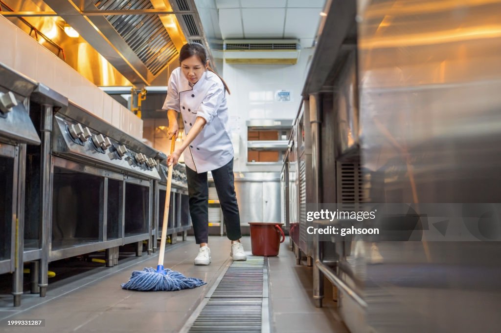 Restaurant employee cleaning floor in kitchen