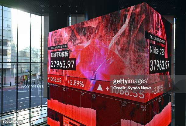 Financial data screens in Tokyo on Feb. 13 show the 225-issue Nikkei Stock Average finishing at 37,963.97, its highest close since January 1990.