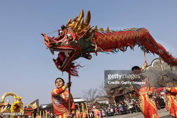 People watch a traditional dragon and lion dance performance during the first day of Spring Festival in Han Kou Li on February 10, 2024 in Wuhan,...