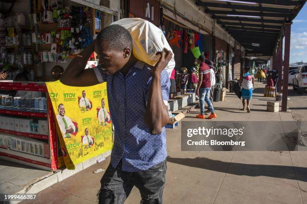 Worker carries a sack of goods in the central business district of Harare, Zimbabwe, on Monday, Feb. 12, 2024. Zimbabwe may back its currency with...