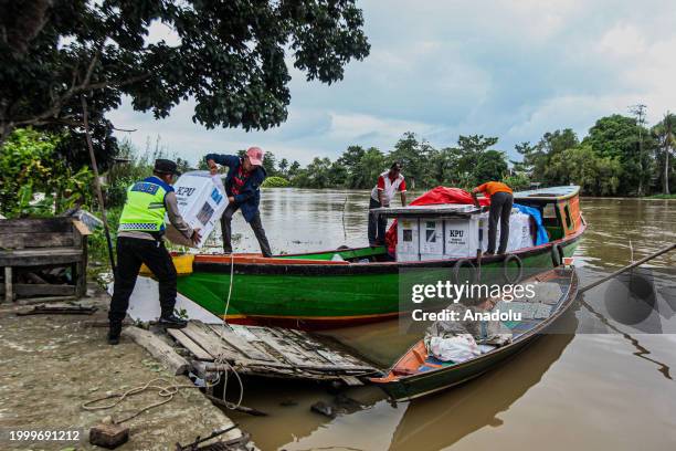 Indonesian election officials transport ballot boxes to a remote village by boat along a river ahead of Indonesian general election in Ogan Ilir,...