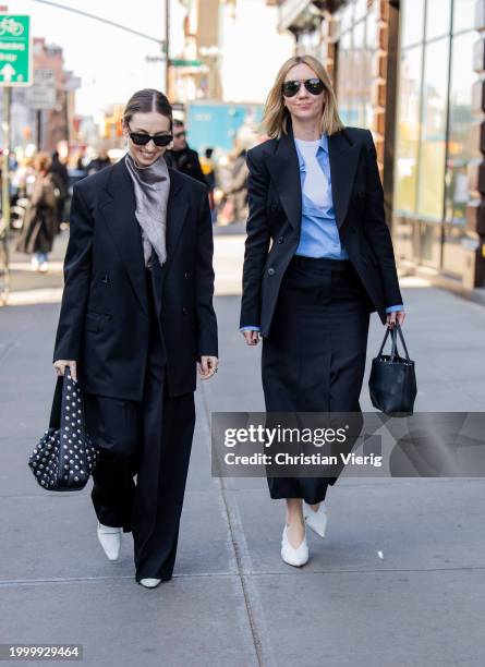 Madeline Harper Fass wears black blazer, pants & Lisa Aiken wears black blazer, skirt, bag outside Helmut Lang on February 09, 2024 in New York City.