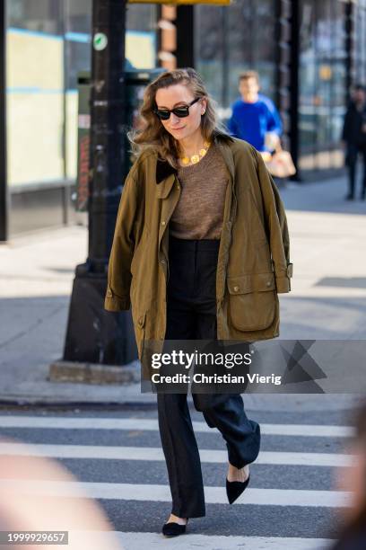 Guest wears khaki jacket, black pants, golden necklace, brown top outside Helmut Lang on February 09, 2024 in New York City.