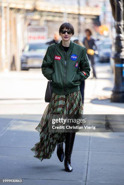 Guest wears asymmetric checkered skirt, bomber jacket outside Helmut Lang on February 09, 2024 in New York City.