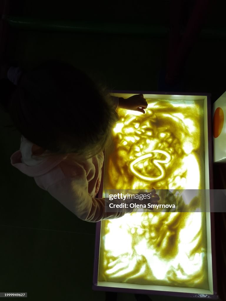 Girl draws a sand animation with her finger on the sand