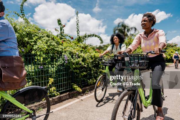 coworkers riding a bicycle at public park - riding bike stock pictures, royalty-free photos & images
