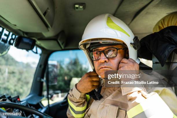 mature fireman putting on helmet - frontline worker car stock pictures, royalty-free photos & images