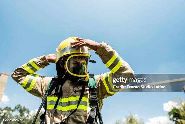 fireman putting on oxygen mask outdoors - firefighter uniform stock pictures, royalty-free photos & images