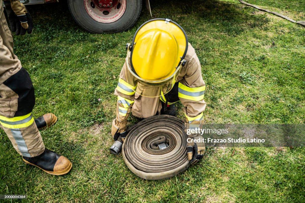 Bombeiro enrolando a mangueira de incêndio