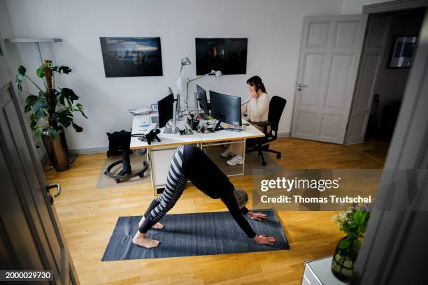 In this photo illustration on the topic of company health management, a woman exercises on a sports mat in front of her desk during her break in the...