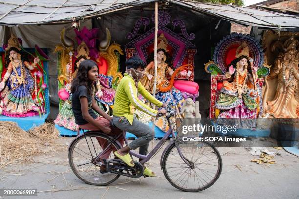 Man rides past the idol of Goddess Saraswati ahead of Vasant Panchami on the 14th of February 2024.