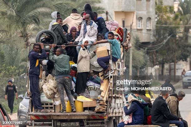 People evacuating from a tent camp ride in the back of a truck with belongings as they flee from Rafah in the southern Gaza Strip on February 13,...
