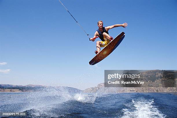 man jumping with wakeboard in lake, view from below - wakeboarden stock-fotos und bilder