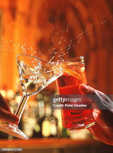 couple clinking glasses, spilling drink, close-up - martini glass stockfoto's en -beelden