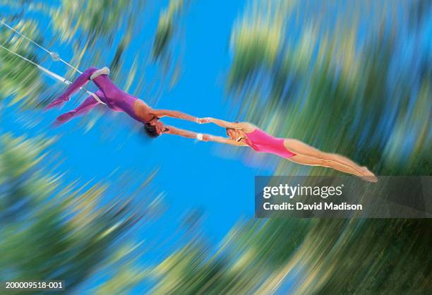 male trapeze artist catching woman, low angle (blurred motion) - toma panorámica fotografías e imágenes de stock