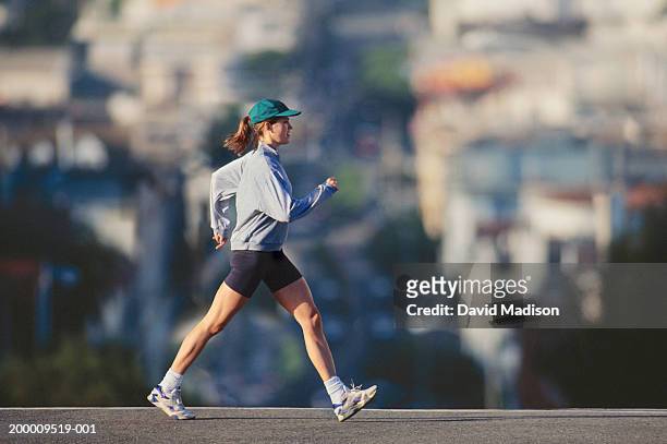 young woman powerwalking in urban area, profile - wielrennerskleren stockfoto's en -beelden