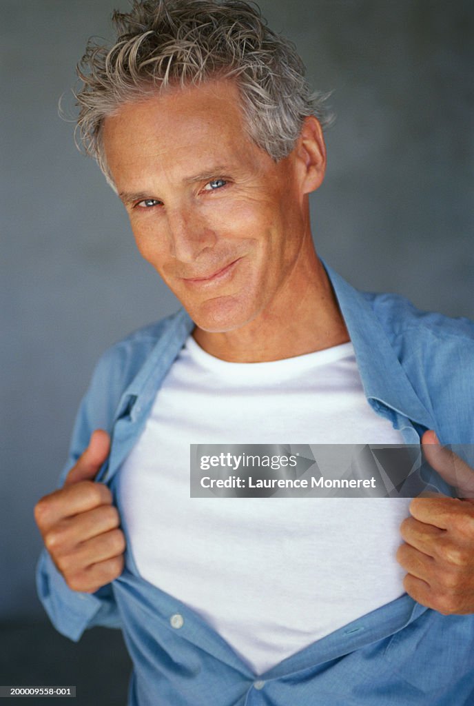 Mature man pulling shirt open, portrait