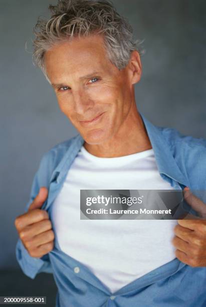 mature man pulling shirt open, portrait - completamente desabrochado fotografías e imágenes de stock