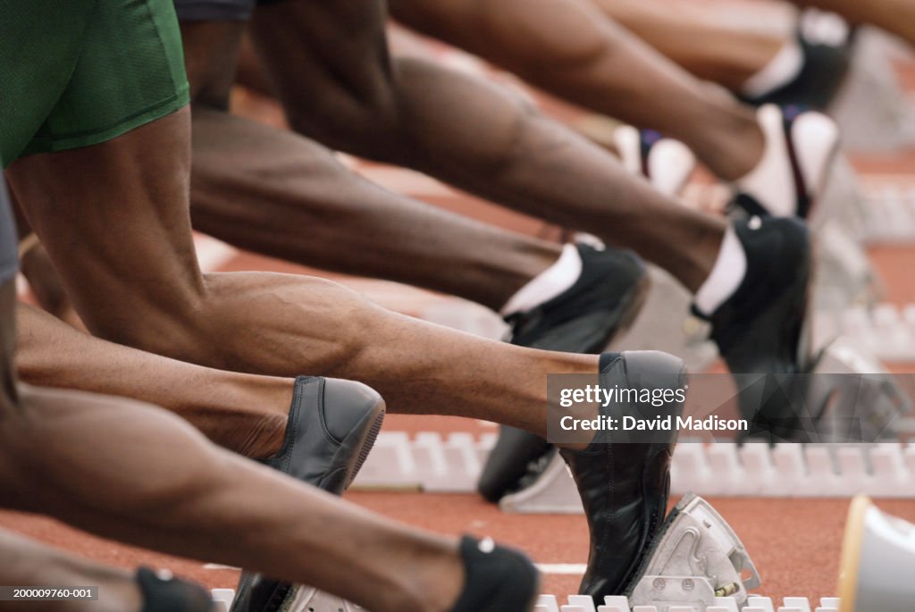 Sprinters' legs on the starting blocks of a men's race, close-up