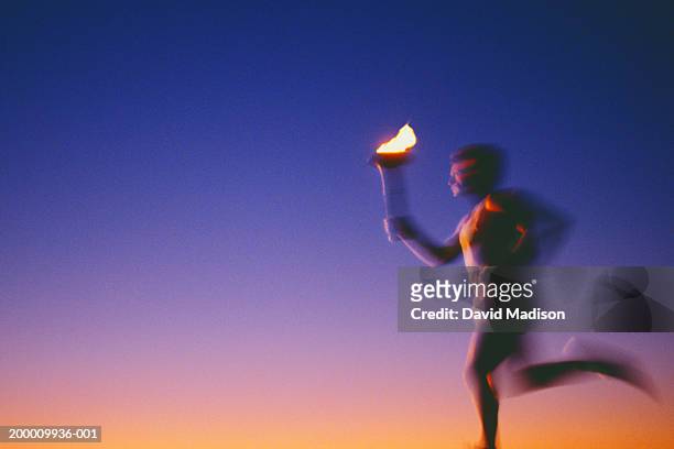 man running with torch at sunset (defocused) - たいまつ ストックフォトと画像