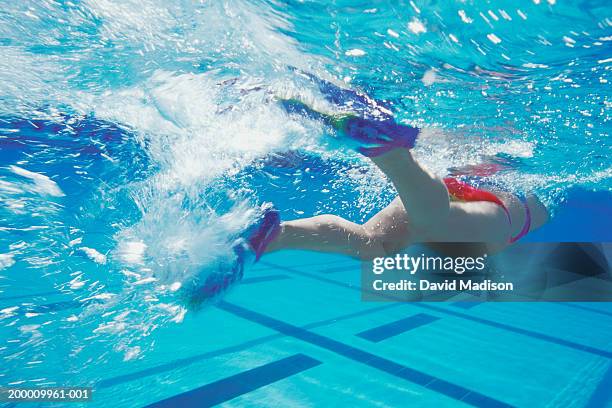 woman swimming in pool with swim fins (rear view) - zwemvliezen stockfoto's en -beelden