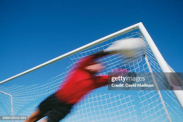 soccer goalie diving for ball, low angle view (blurred motion) - goal posts stockfoto's en -beelden