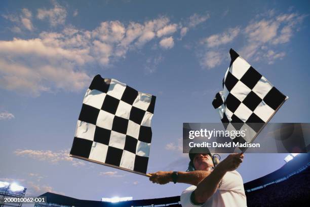 male race official waving checkered flags, low angle view - bandeira de chegada imagens e fotografias de stock