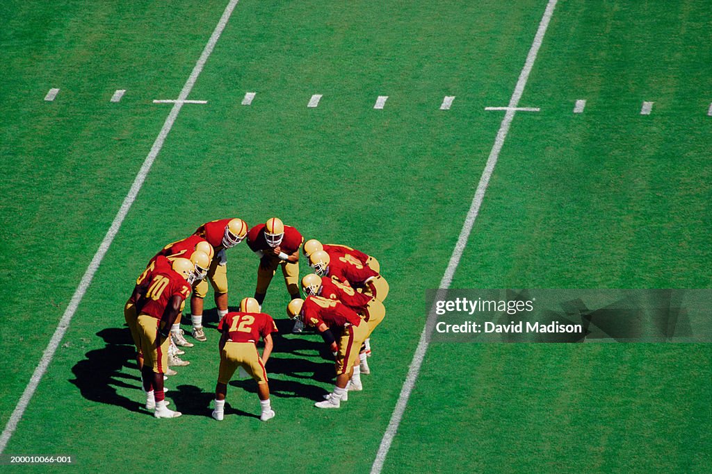 American football players standing in huddle on field, high angle view