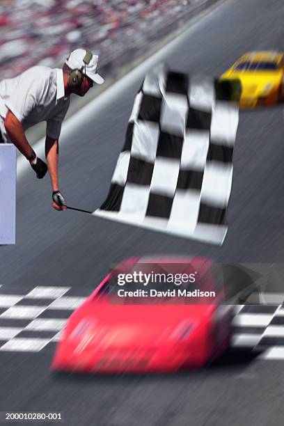race official waving checkered flag above race car(blurred motion) - race official stock pictures, royalty-free photos & images