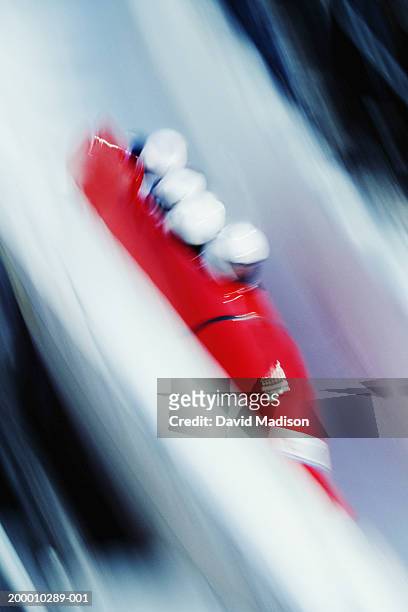 four-man bobsled racing down course (blurred motion) - bobsleigh stockfoto's en -beelden