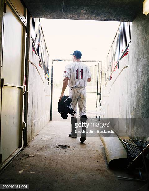 baseball player walking through stadium tunnel, rear view - baseball stadiums stock pictures, royalty-free photos & images