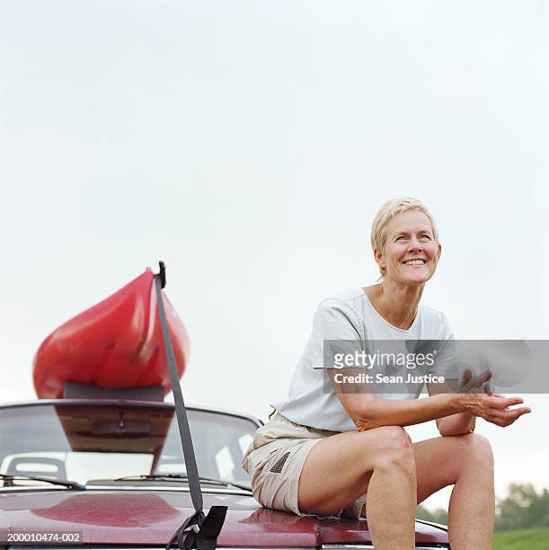 mature woman sitting on car with kayak, portrait - sitting on top of car stock pictures, royalty-free photos & images