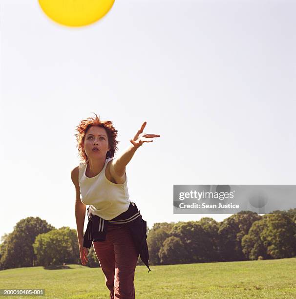 woman throwing flying disc in park - throwing frisbee stock pictures, royalty-free photos & images