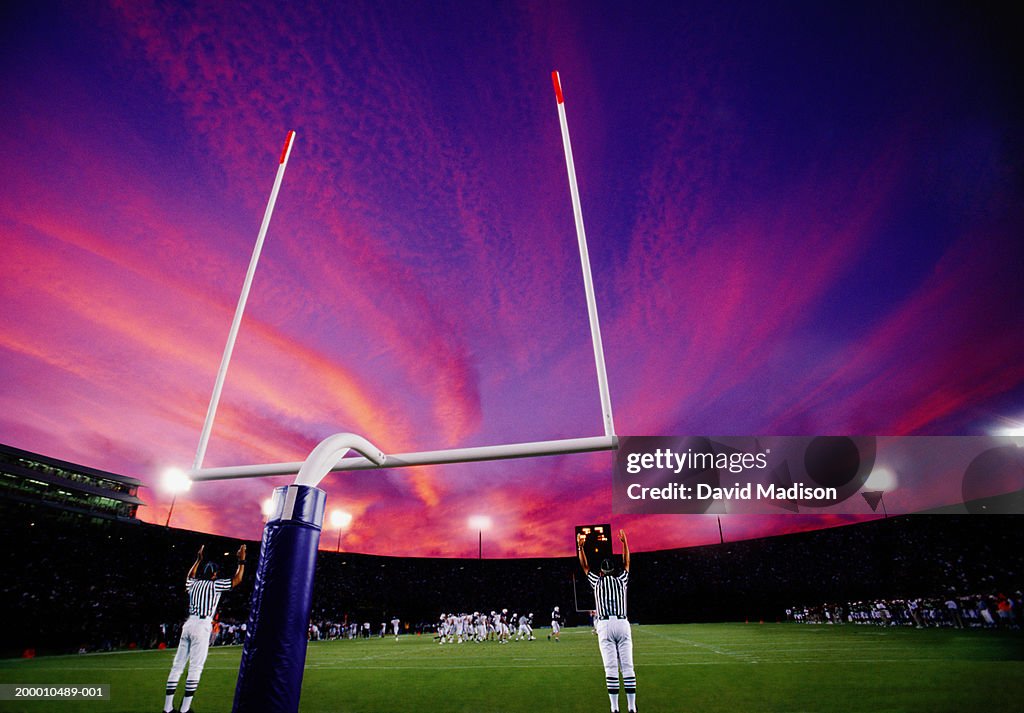 Referees signaling field goal at American football game, sunset