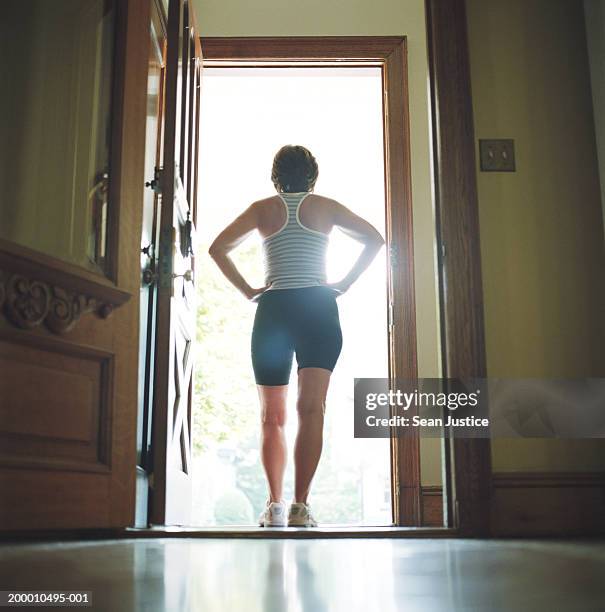 woman standing in doorway, rear view - open workouts stockfoto's en -beelden