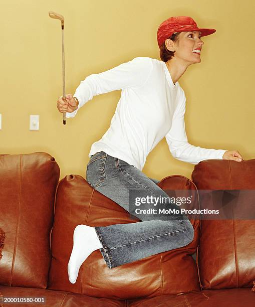 woman with jockey's hat and whip on couch, profile - female whipping stock-fotos und bilder