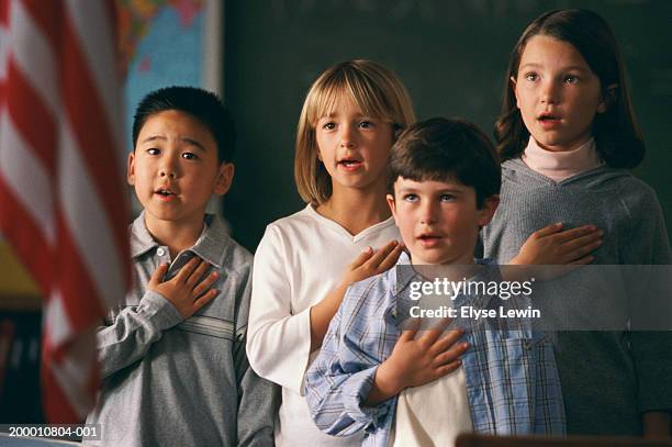 four children (5-9 years) reciting pledge of allegiance to us flag - oath fotografías e imágenes de stock