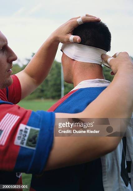 rugby player bandaging teammate's head, close-up - head injury fotografías e imágenes de stock