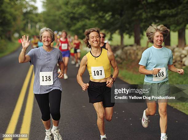 three happy women running in road race - marathon stock-fotos und bilder