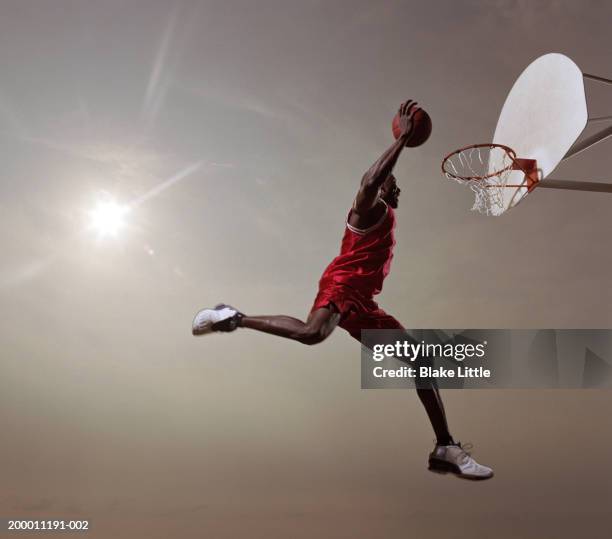 basketball player in mid-air jump, about to slam dunk basketball - basketball shoe stock-fotos und bilder