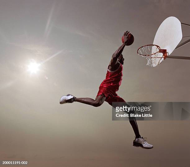 basketball player in mid-air jump, about to slam dunk basketball - basketball shoe fotografías e imágenes de stock