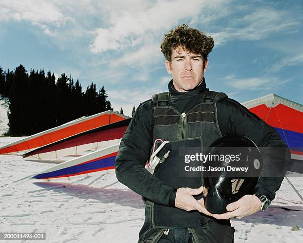 man in black outfit holding helmet, hang glider in background - hang glider stock pictures, royalty-free photos & images