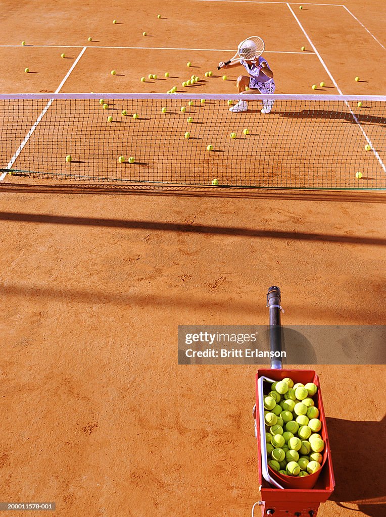 Female tennis player guarding face with racquet on court