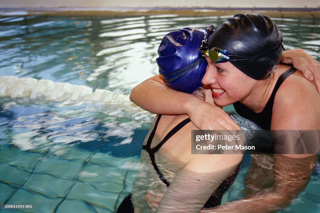 Two female swimmers embracing in pool