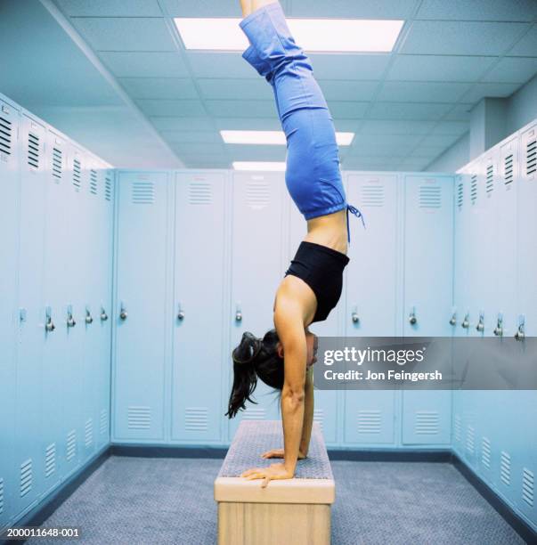 young woman doing hand stand on bench in locker room - handstand stock pictures, royalty-free photos & images