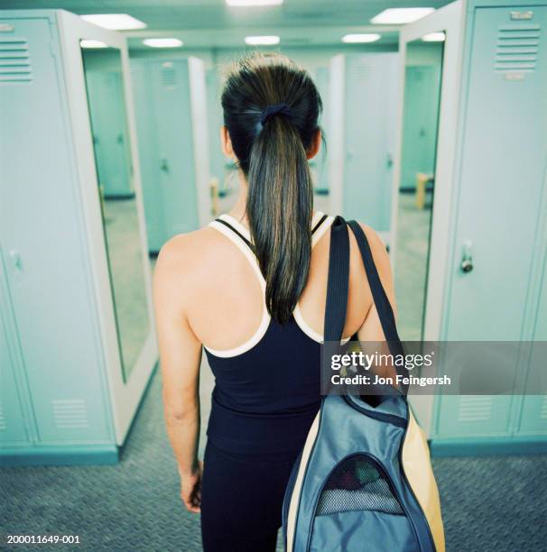 young woman in locker room, rear view - sporttas stockfoto's en -beelden